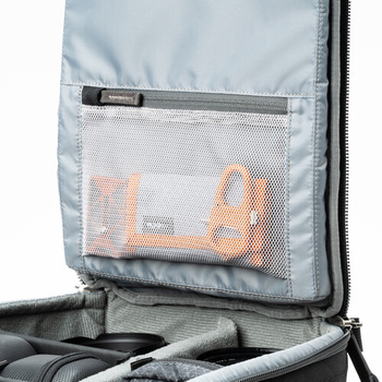 Interior view of a camera backpack with mesh pocket displaying orange lens cases and organized gear compartments.