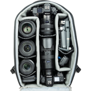 Overhead view of a camera backpack with organized compartments displaying professional photography gear including lenses, camera body, tripod, and accessories.