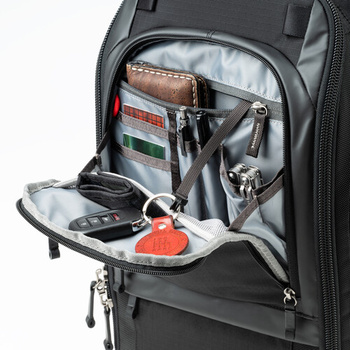 Open camera backpack organizer compartment displaying storage pouches, cables, and small accessories.