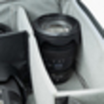 Camera lens stored in white padded compartment of photography equipment case.