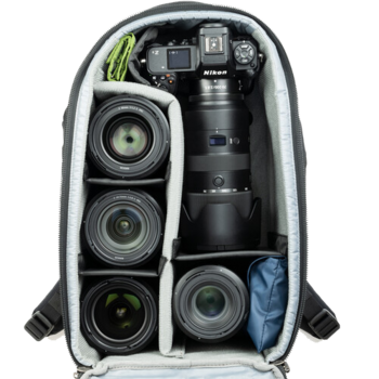Camera backpack with organized compartments displaying a Nikon DSLR body, multiple lenses, and accessories.