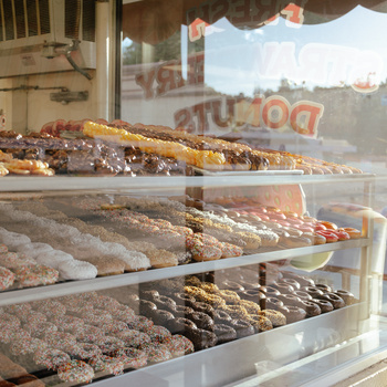 Bakery display window with shelves of assorted baked goods including pastries, breads, and decorated items.