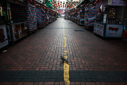 Symmetrical view down a covered market arcade with shops on both sides, yellow center line, and decorative overhead lighting.
