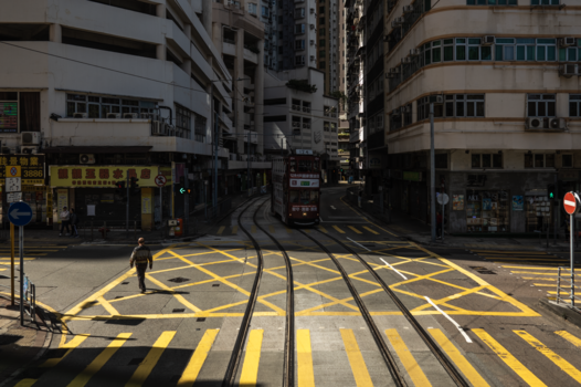Tram tracks and yellow pedestrian crossings on an urban street surrounded by multi-story buildings.