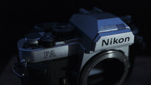 Nikon FA film camera body shown in profile against a dark background with dramatic blue lighting.