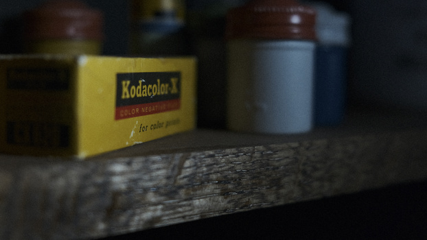 Vintage Kodacolor film box and darkroom bottles arranged on weathered wood surface.