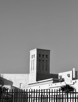 Black and white architectural photograph of a modernist tower building with horizontal striping against a clear sky.