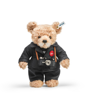 Teddy bear wearing a black jacket with patches and a stethoscope around its neck.