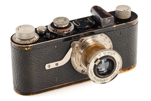 Vintage rangefinder camera with black leather body and brass lens assembly, viewed from above at three-quarter angle.