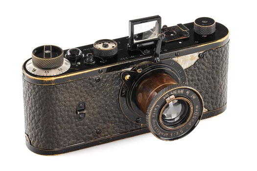 Vintage rangefinder camera with textured black body and brass accents, featuring a bright lens and dual focusing knobs.