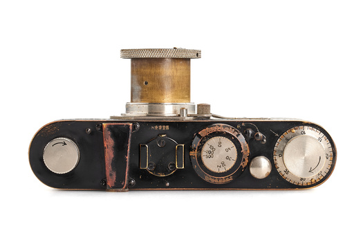 Top view of a vintage rangefinder camera with wooden top plate and black baseplate showing internal mechanisms.