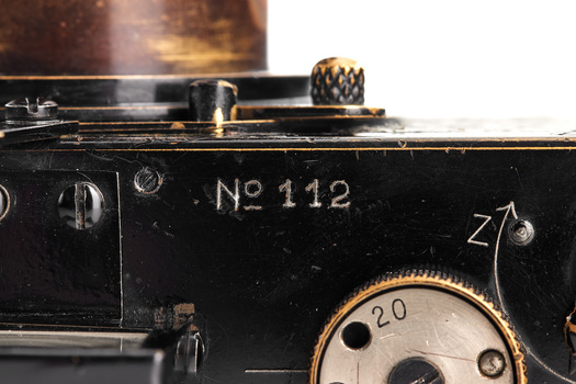 Close-up detail of vintage camera body showing serial number 112 and mechanical shutter dial.