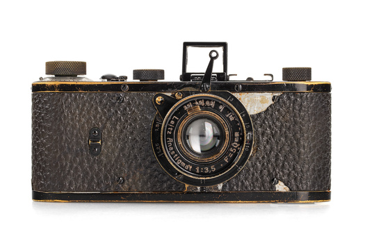 Vintage rangefinder camera with textured leather body, brass trim, and mechanical top plate controls.