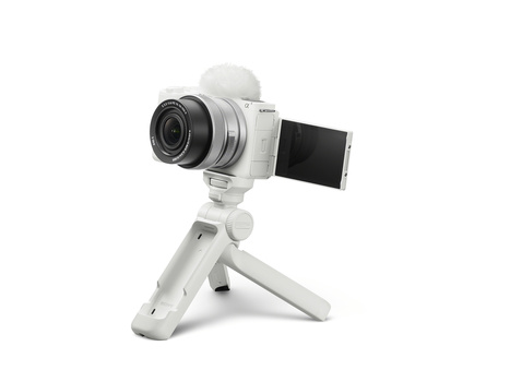 White mirrorless camera with articulating screen mounted on white tripod stand.