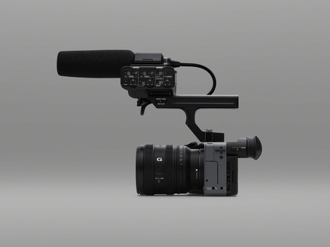 Professional cinema camera with mounted audio recorder and microphone boom on gray background.