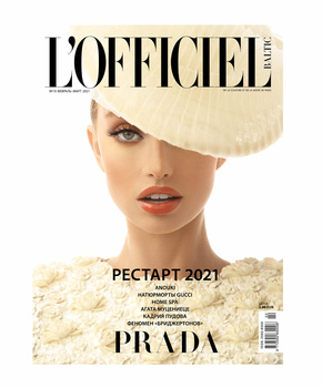 Magazine cover featuring a model wearing a large cream-colored sculptural hat against a pale background.