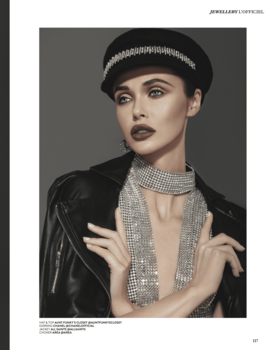 Portrait of a person wearing a black leather jacket, rhinestone-studded choker, and knit beanie against neutral background.