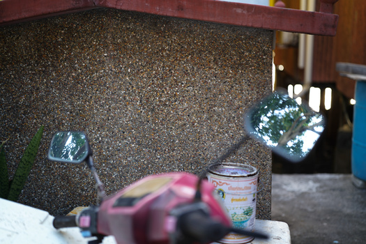 Close-up of a textured granite or aggregate countertop with blurred objects in the foreground and background.