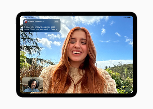 Screenshot of a video call interface showing a woman with long reddish-orange hair smiling at the camera outdoors.