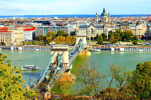 Chain Bridge spanning a turquoise river with a domed basilica and cityscape beyond.