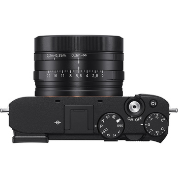 Top-down view of a black mirrorless camera with attached prime lens and visible control dials.