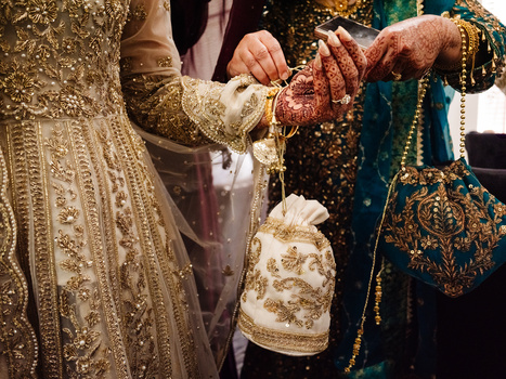 Hands exchanging a decorated pouch during an ornate ceremonial ritual with gold embroidery.
