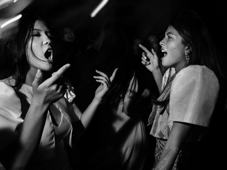 Two women facing each other with animated expressions and hand gestures in dramatic black and white lighting.