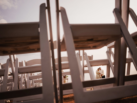 Wooden chairs arranged in rows with dramatic backlighting creating strong shadows and depth of field.