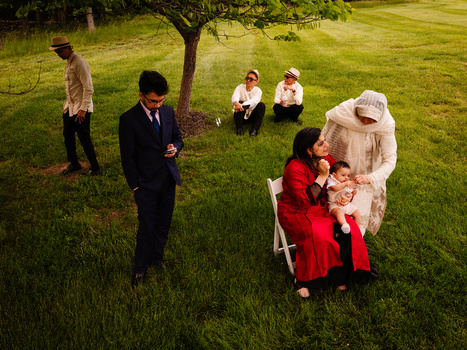 Family gathering on a lawn with multiple generations standing and sitting in casual dress and formal attire.
