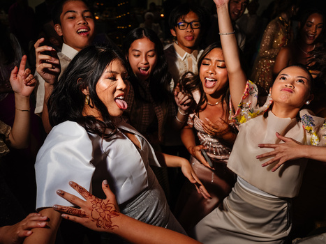 Group of people dancing and celebrating at a nighttime indoor party with warm ambient lighting.