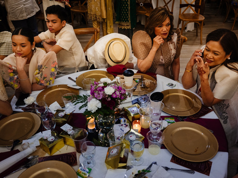 Family gathered around an elegantly decorated outdoor dinner table with floral centerpiece and place settings.