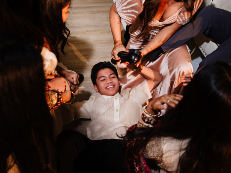 Man in white shirt lying on floor surrounded by people dancing and celebrating overhead view.