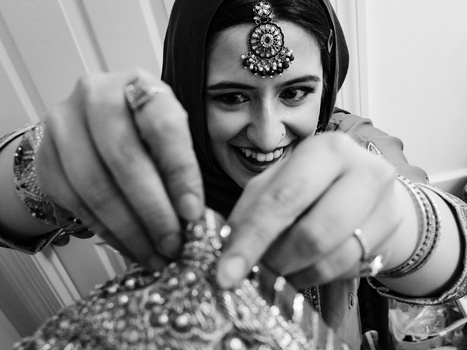 Woman in traditional attire displaying ornamental jewelry and beaded accessories with animated gesture.
