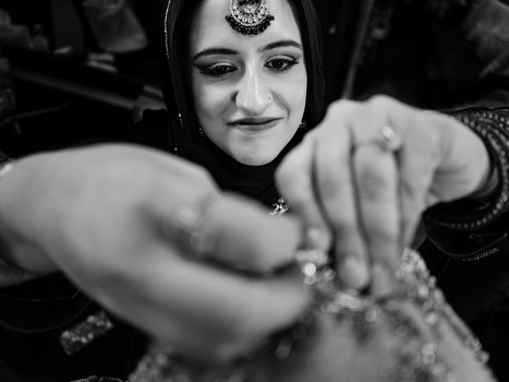 Woman in traditional South Asian bridal attire with ornamental jewelry, hands raised in a gestural pose.