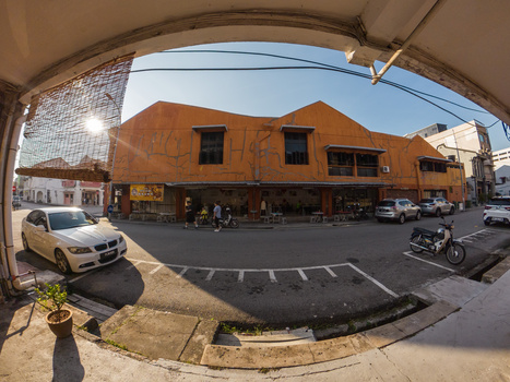 Fish-eye view of a street corner with orange brick building and parked vehicles.