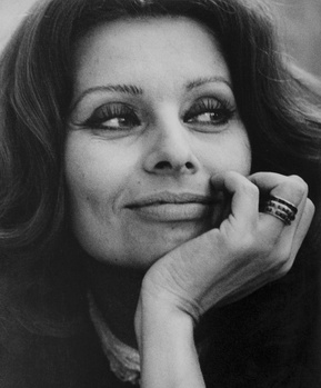 Black and white portrait of a woman with long dark hair, hand raised thoughtfully to her face.