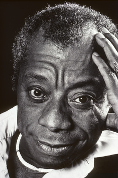 Black and white portrait of a man with his hand to his head, direct gaze toward camera.