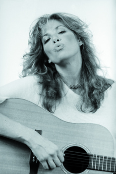 Black and white portrait of a woman with long wavy hair holding an acoustic guitar.