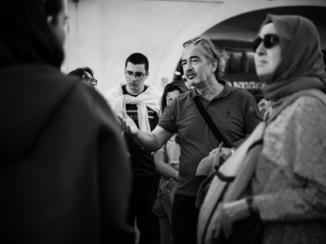 Group of people gathered indoors during a conversation or event, shot in black and white.