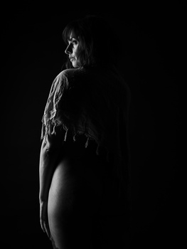 Profile view of a person in dramatic side lighting against a black background.