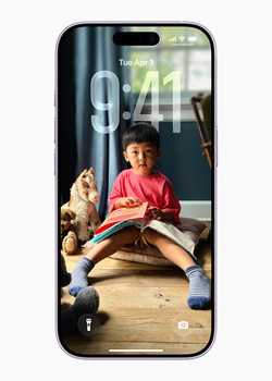 Smartphone displaying lock screen with child reading beside a dog indoors.