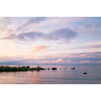 Calm water at sunset with islands silhouetted against pink and purple clouds.