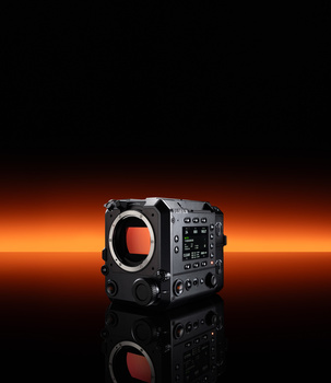 Professional cinema camera body with exposed red sensor and control panel against dark background.