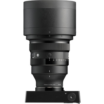 Black telephoto lens mounted on a display stand, showing the barrel, focus ring, and lens hood.