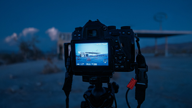 DSLR camera on tripod displaying live preview of architectural structure during blue hour photography session.
