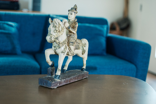 Decorative figurine of a mounted figure on horseback displayed on a table in front of a blue couch.