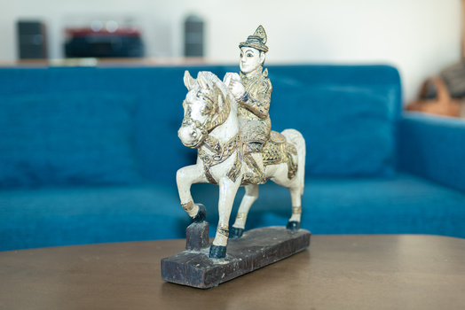 Decorative brass figurine of a person riding a horse on a black rectangular base.