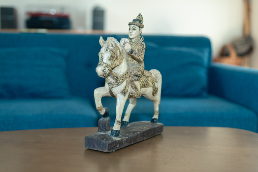 Ornamental figurine of a robed figure mounted on a decorative horse, displayed on a dark base.