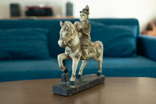 Ornamental figurine of a figure riding a decorated horse, mounted on a dark base.