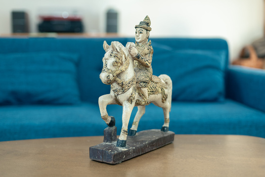 Ornamental brass figurine of a regal rider on horseback mounted on a dark rectangular base.